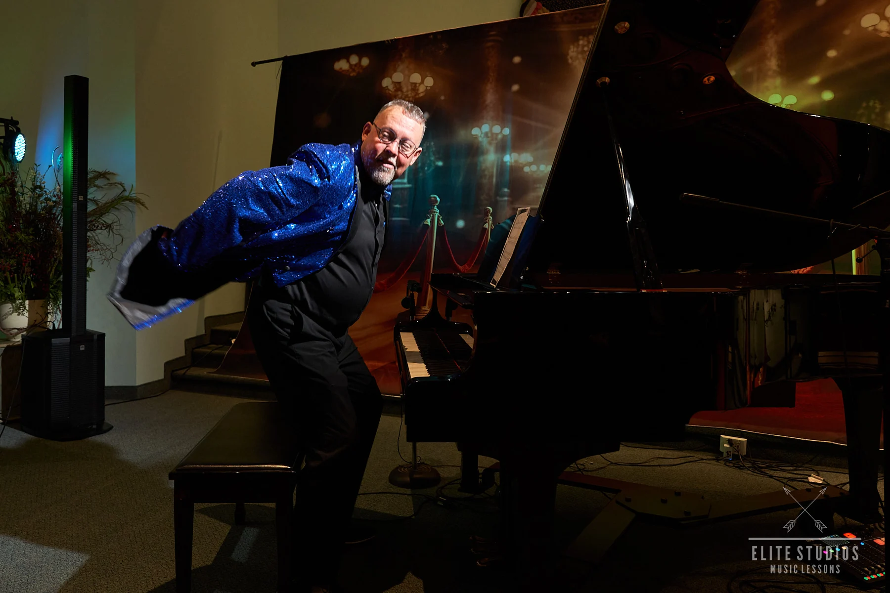A performer beside a grand piano at an Elite showcase