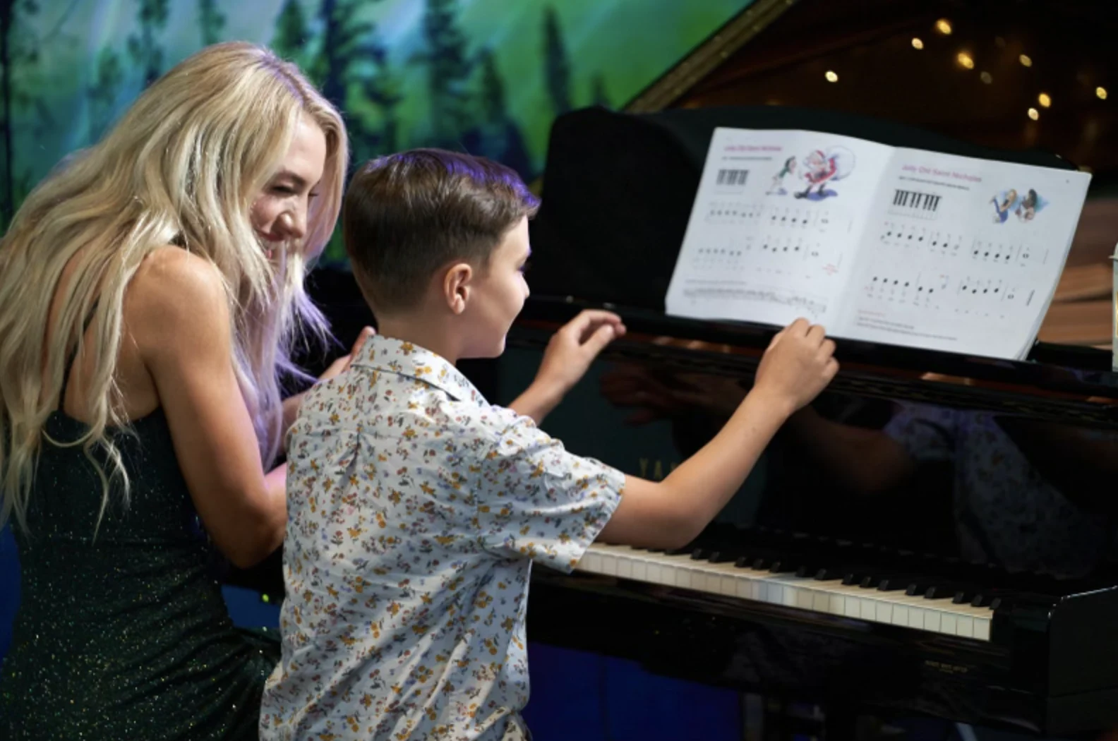 A teacher supporting a young student at the piano